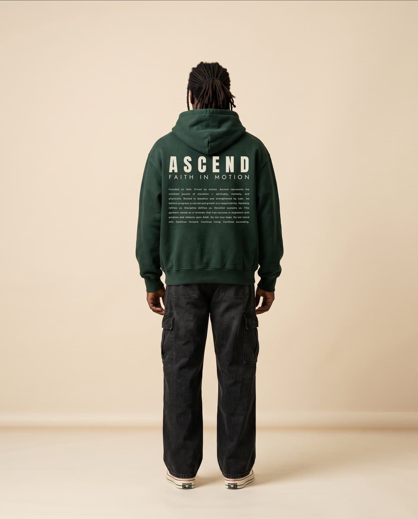 A man stands facing away in the Dark Green hoodie, the ASCEND lockup and manifesto printed across the back